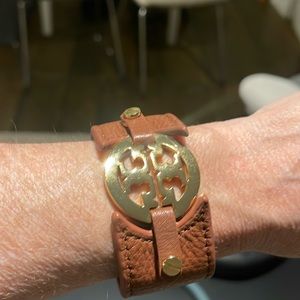 Tory Burch Reva logo cuff bracelet in brown leather with gold hardware.